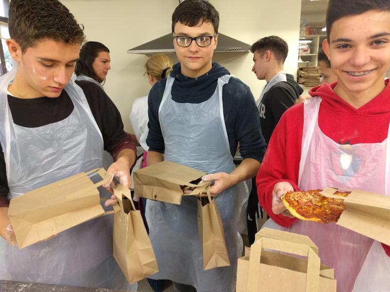 Chicos con delantales de plástico y pizzas en el curso de idiomas en irlanda 
