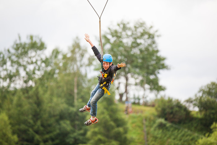 Joven lanzandose en tirolina en el campamento de verano en el extranjero
