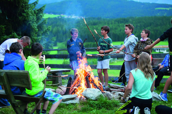 Grupo de jovenes disfrutando de la fogata en el campamento de verano en el extranjero