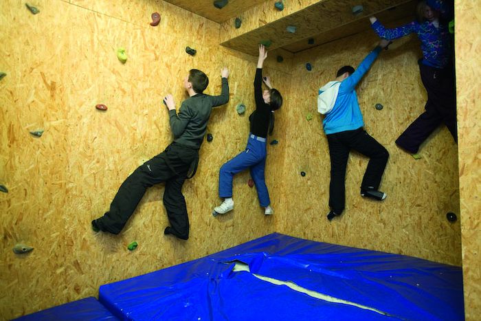 Grupo de jovenes practicando escalada en el rocodromo del campamento de verano en holanda