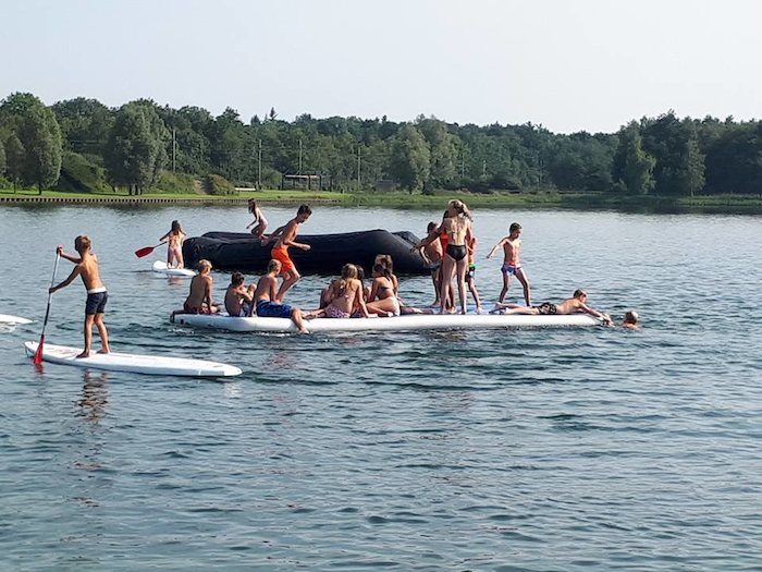 grupo de jovenes practicando actividades acuaticas en el lago del campamento de verano en holanda