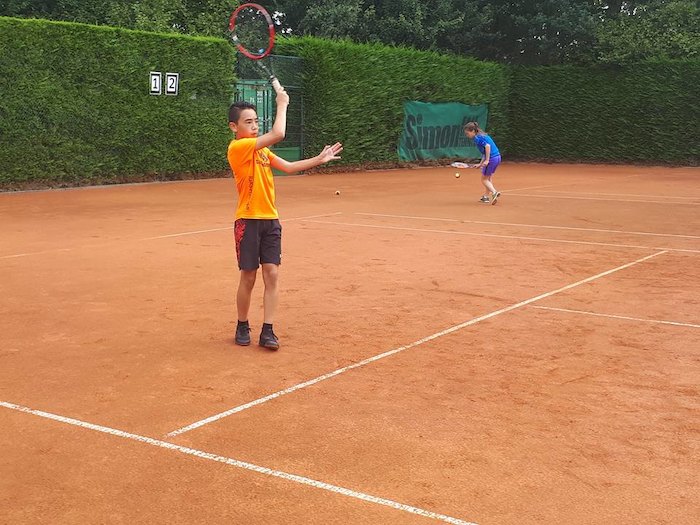 duo de niños practicando tenis en equipo en el campamento de verano en holanda