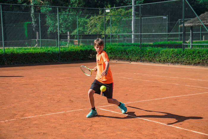 niño jugando al tenis en las canchas del campamento de verano en holanda