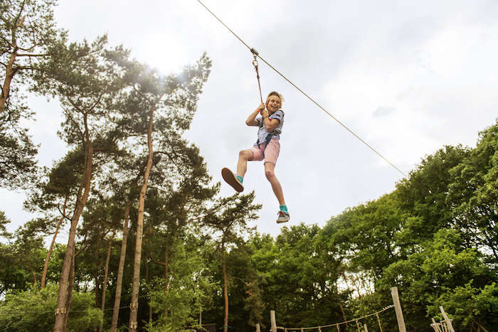joven en una tirolina durantes las actividades multiaventura del campamento de verano en holanda