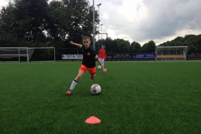 Joven entrenando en el campo de futbol del campamento de verano en holanda