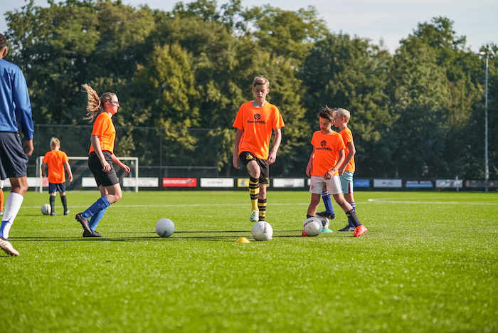 Grupo de jovenes disfrutando de un partido de futbol en el campamento de verano en holanda