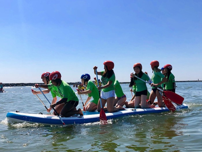 grupo de jovenes remando juntos en la paddle surf del campamento de verano en holanda