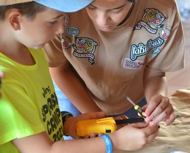 Niño con un walkie talkie y un destornillador en el campamento