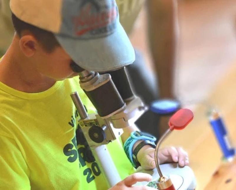 Niño usando un microscopio en el campamento