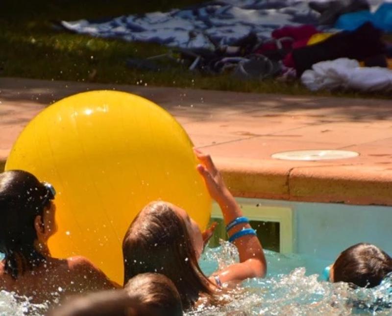Niños en la piscina con una pelota amarilla en el campamento