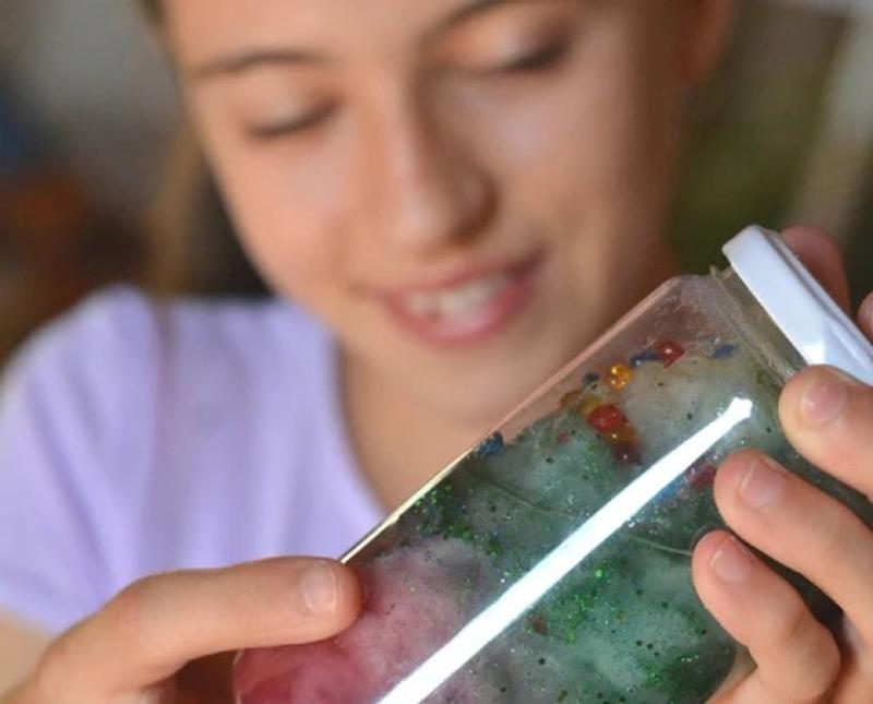 Niña sujetando un bote con un experimento en el campamento