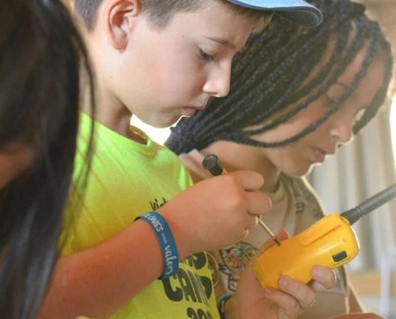 Niño desmontando un walkie talkie en el campamento