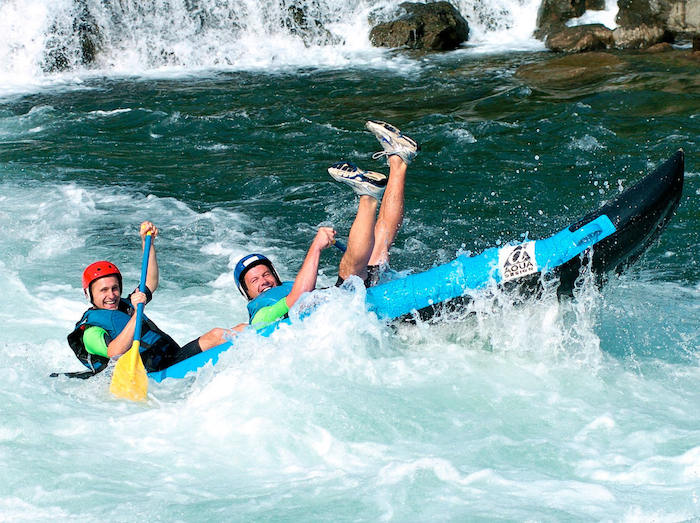 jóvenes cayéndose del kayak en el río del campamento de surf en Francia