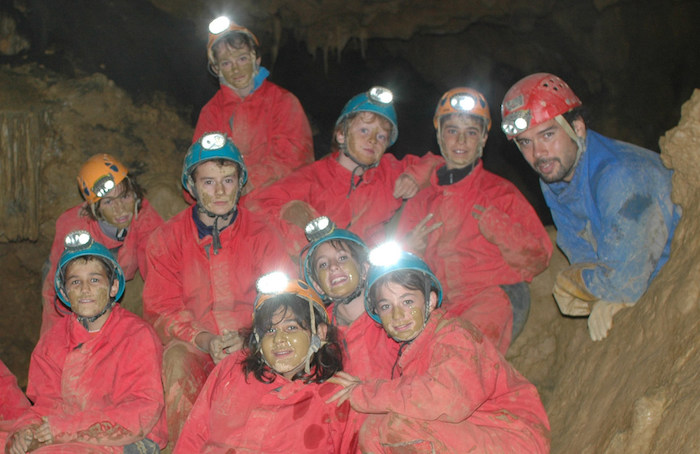 jóvenes en el interior de una cueva con sus monitores del campamento de verano en Francia