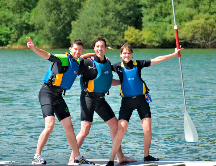 jóvenes practicando paddle surf en el río del campamento de verano en agosto