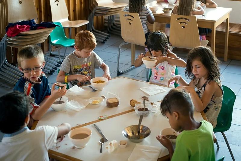 niños tomando el desayuno en el campamento de verano en francia