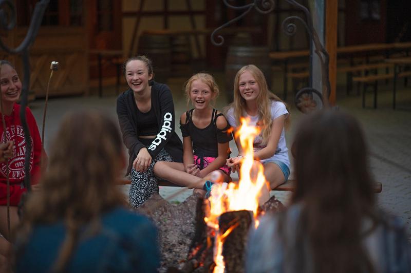 grupo de chicas escuchando musica durante una fogata en el campamento de verano en alemania