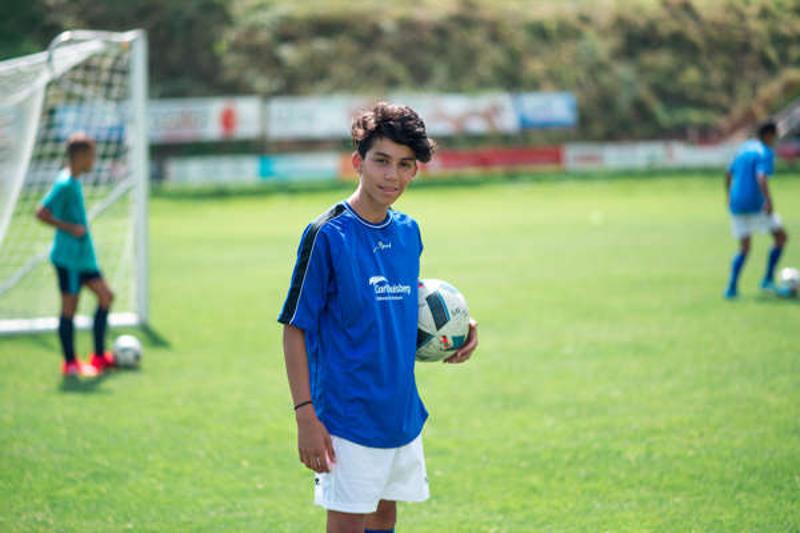 niños con balon en el campo de futbol antes de una competicion en el campamento de verano de futbol