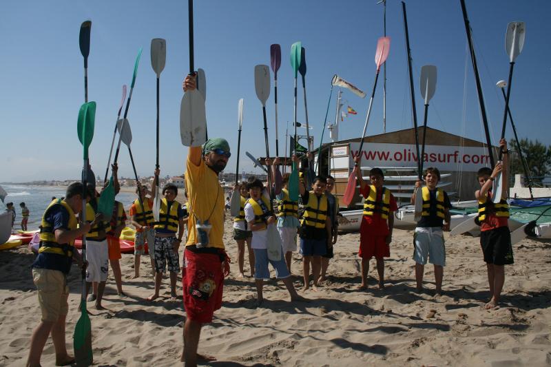 Campistas y monitor con las palas en alto en la playa en colonia náutica en Valencia