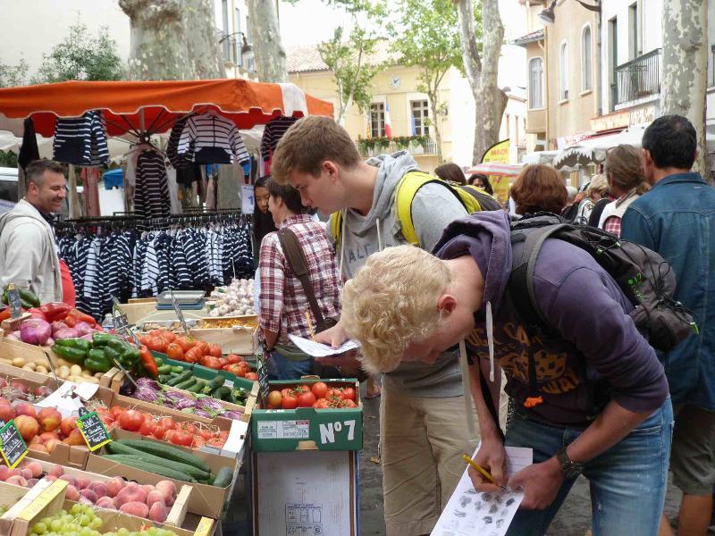 jovenes apuntando los datos de la fruta en el mercado del campamento de verano en francia