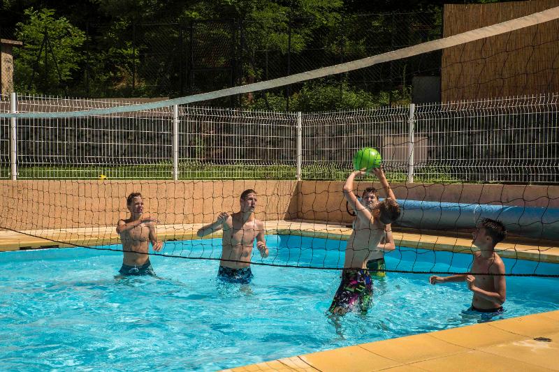 Chicos jugando al volleyball en la piscina en el curso de idiomas en verano