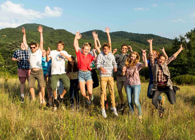 Grupo de jovenes saltando divertidos por la naturaleza del campamento de verano en francia