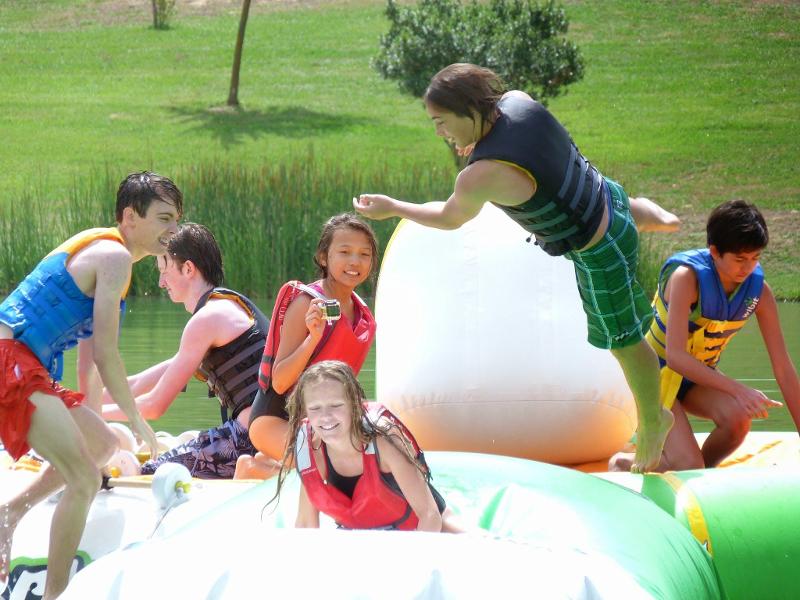 Grupo de jovenes disfrutando de las colchonetas acuaticas en el campamento de verano en francia
