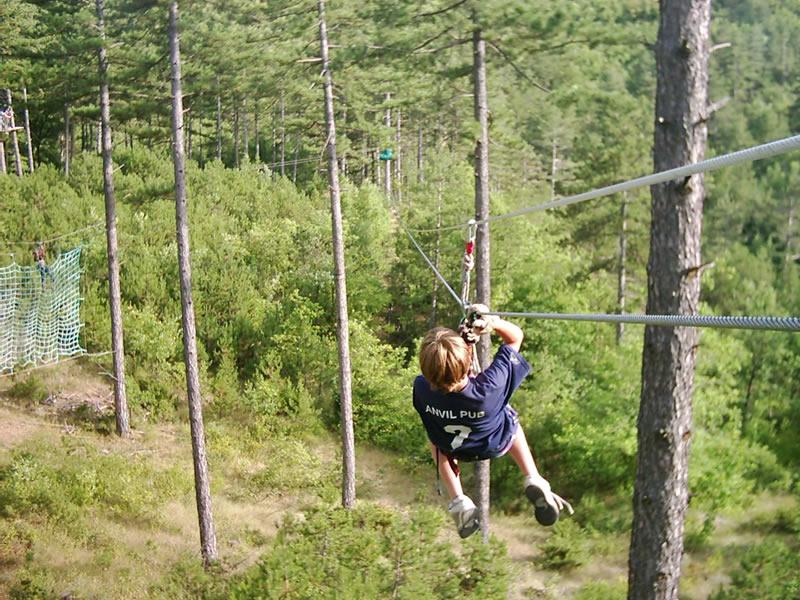 Niño haciendo tirolina en la naturaleza del campamento multiaventura en francia