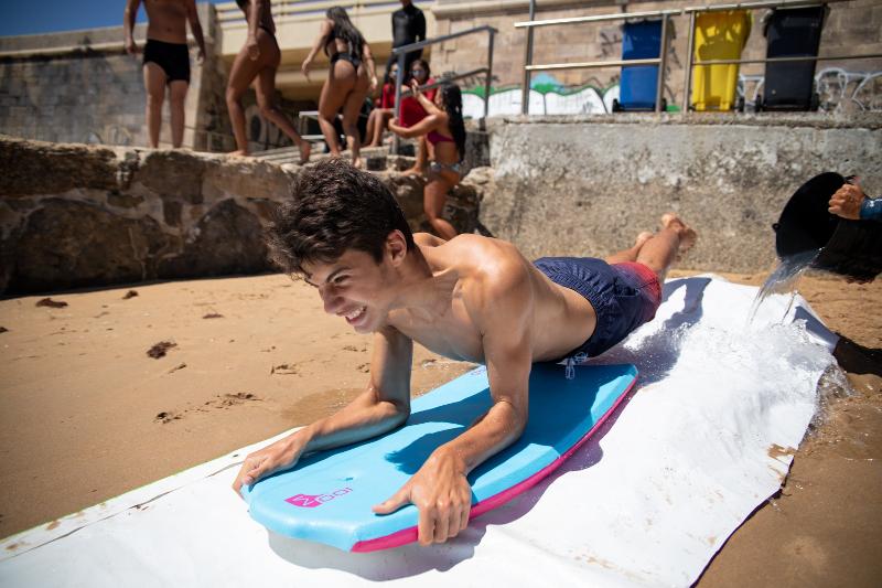 Chico adolescente tirándose por una lona con su body board del campamento de surf en Somo