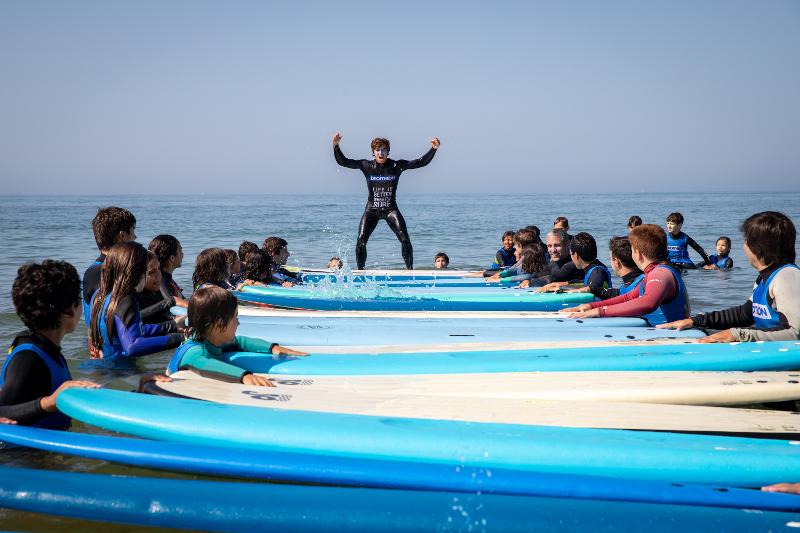 Participantes del campamento de surf Salinas jugando a juegos en la playa con las tablas