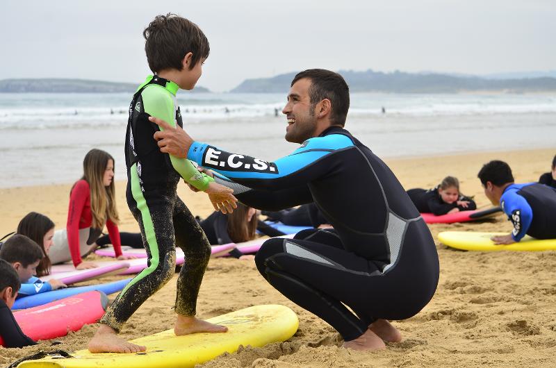 Niño practicando surf con el entrenador del campamento de verano en Cantabria 