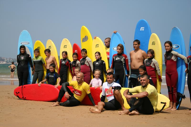 grupo de niños con sus tablas de surf en la playa del campamento de verano en Cantabria