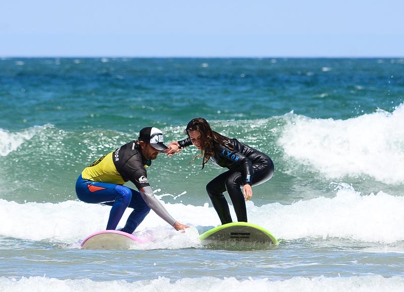 Monitor y chica surfeando en surfcamp en cantabria