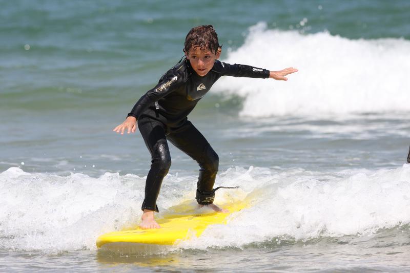 Niño surfea las olas en surfcamp en cantabria
