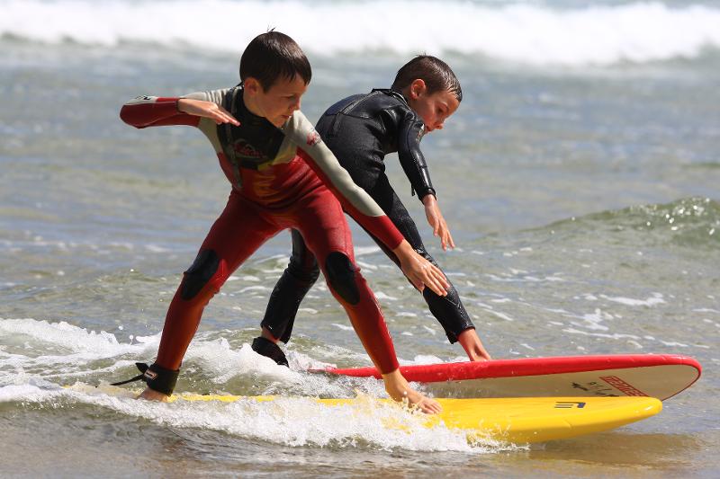 Dos niños surfean las olas en surfcamp en cantabria