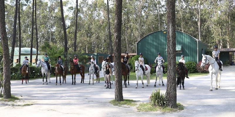 grupo de jovenes preparados para salir con los caballos en el campamento de hipica en portugal