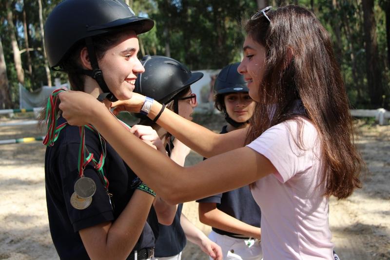 niñas poniendo de la medalla por haber participado en el campamento hipico en portugal