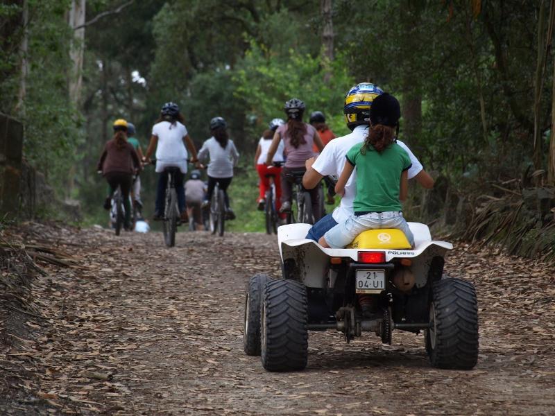 grupo de niños haciendo actividades multiaventura con quads y bicicleta en el campamento de verano en portugal