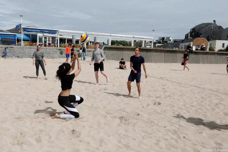 Niños y niñas jugando al voleibol en la playa en el surfcamp francia 
