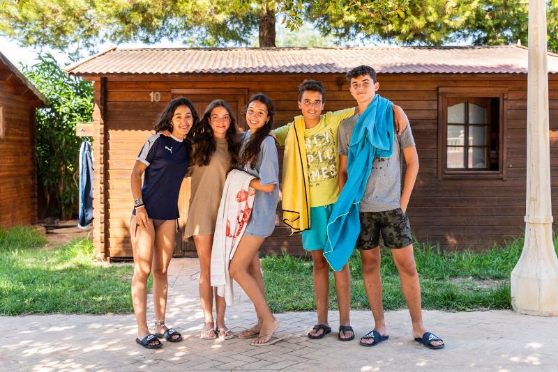 Tres chicas y dos chicos con toallas frente a las casetas en el curso de ingles en eeuu
