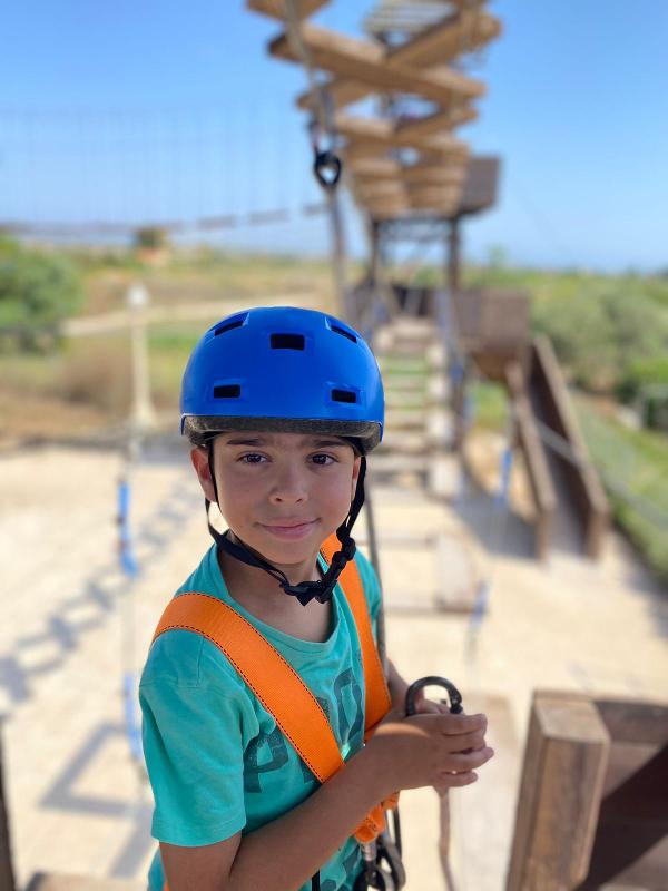 Niño con casco azul preparándose para la tirolina en el curso de ingles en eeuu