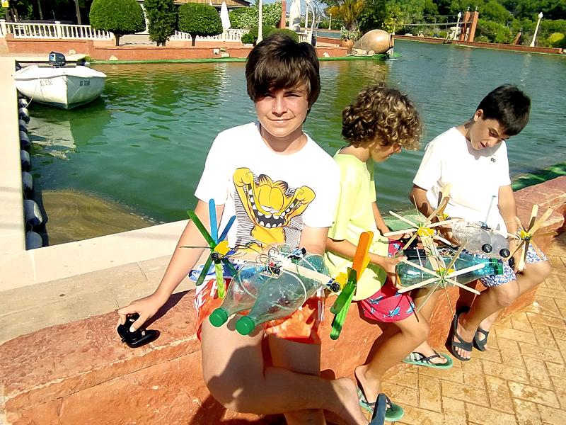 Tres niños con sus invenciones hechas con materiales reciclables en el campamento verano alicante