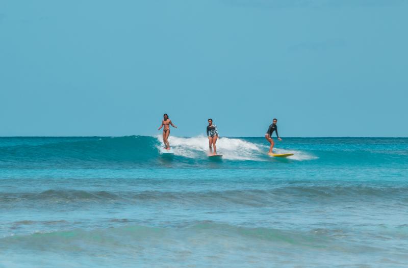 Mar azul y tres campistas surfeando a lo lejos en el campamento verano alicante