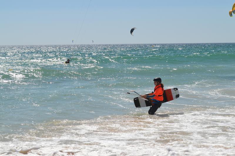 Joven entrando al mar para hacer windsurf en los campamentos de verano de 15-18 años