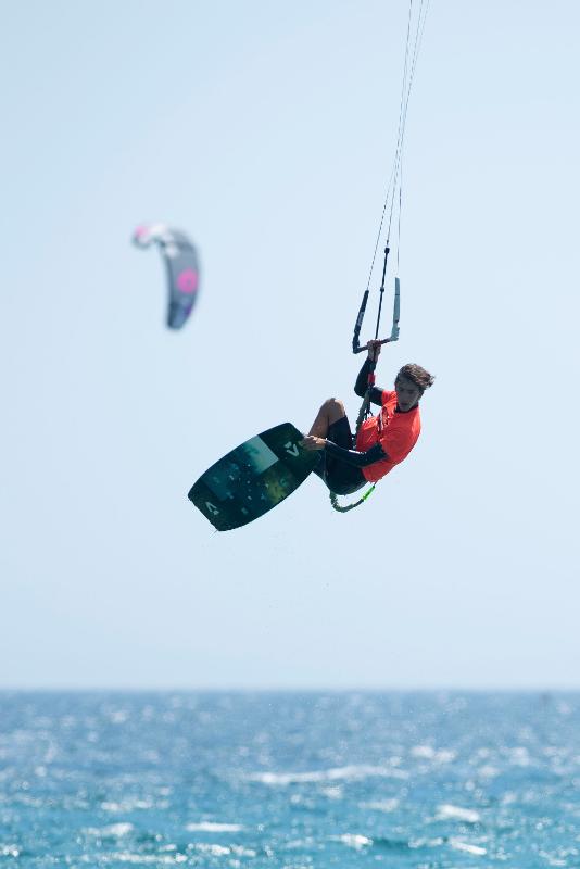 Joven saltando en el aire con su tabla de Kitesurf en el campamento de verano en Cádiz
