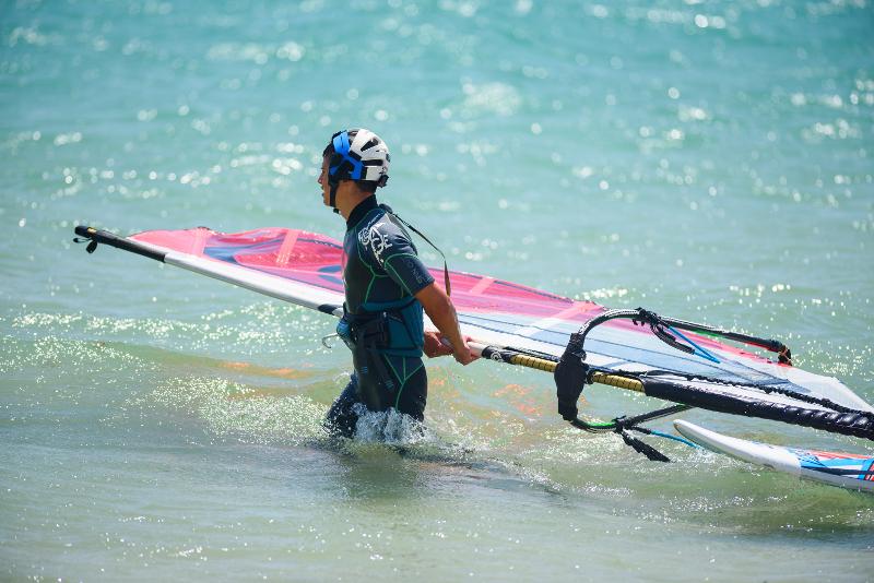 Chico llevando su tabla de Kite en el mar en el campamento de verano en Cádiz