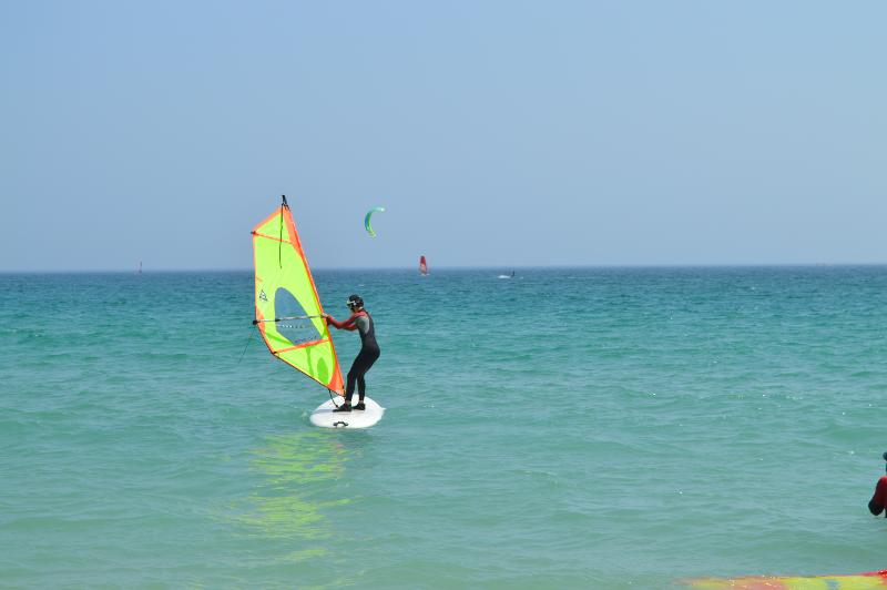 Joven sujetando la vela de Windsurf durante las clases del campamento de verano en Cádiz