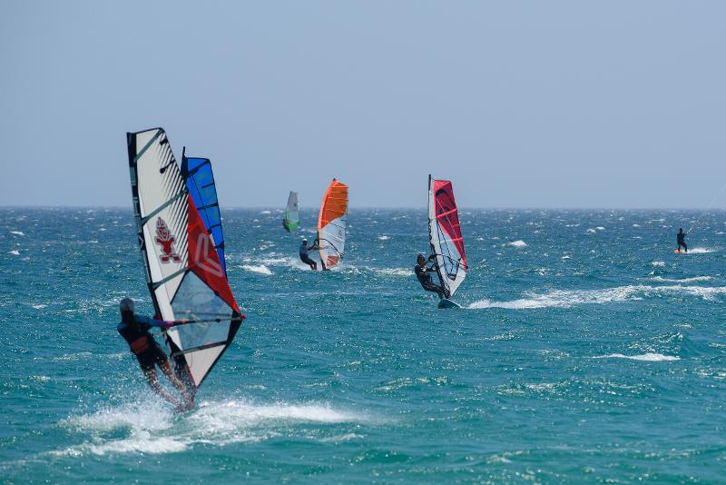 Seis campistas haciendo Windsurf en el mar en el campamento de verano en Cádiz