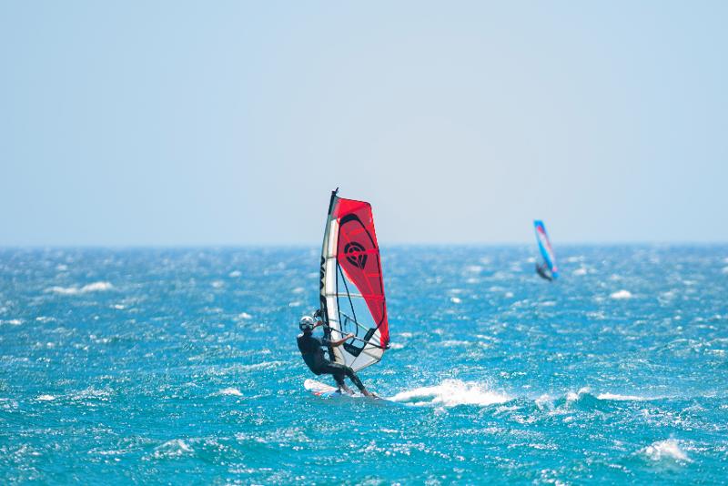 Chico haciendo Windsurf en un mar azul en el campamento de verano en Cádiz