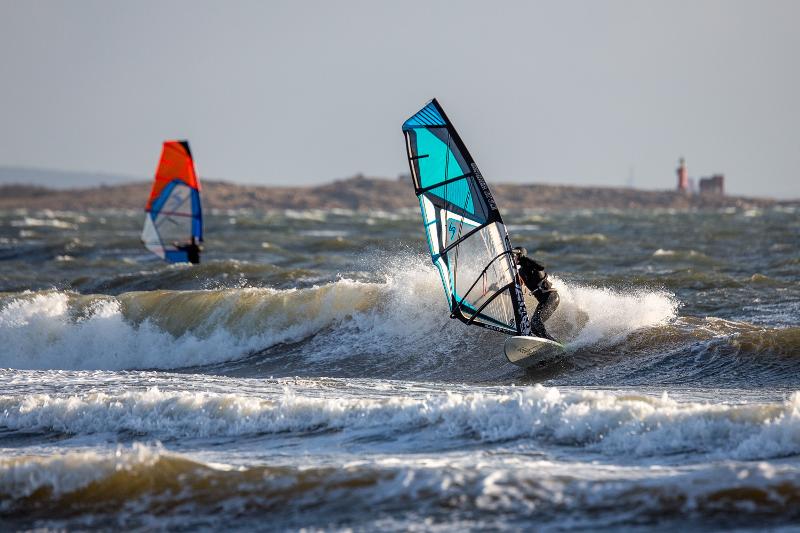 Jóvenes practicando Winsurf en la playa con muchas olas durante el campamento de verano en Cádiz